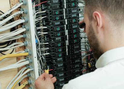 Moore & Russell electrical technician examining wiring connections inside a circuit breaker panel for a residential service check. Moore & Russell electrical technician examining wiring connections inside a circuit breaker panel for a residential service check.