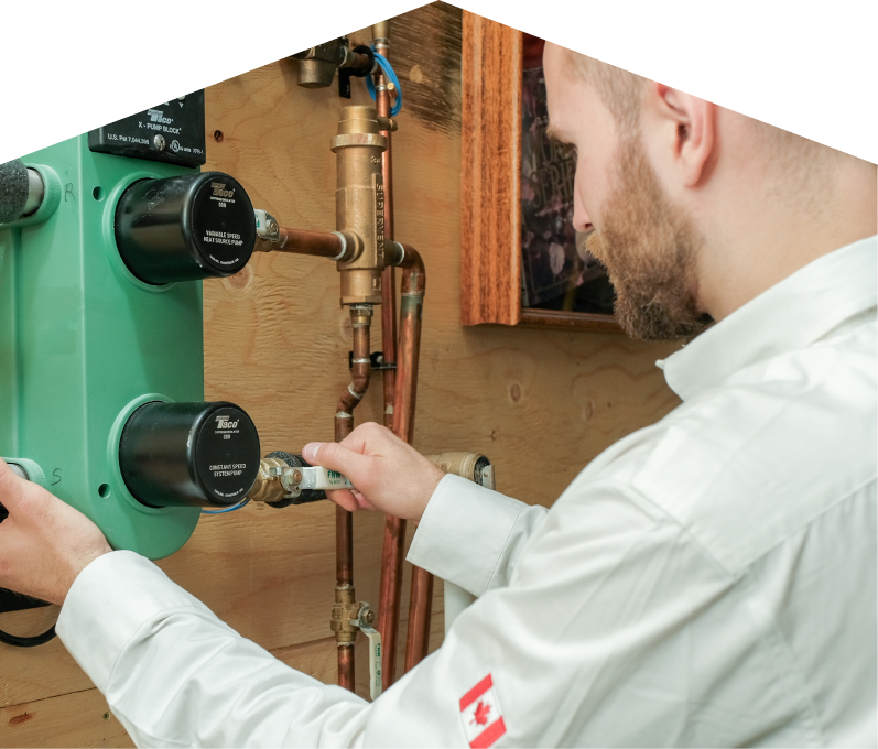 Moore & Russell HVAC specialist performing boiler installation, securing a valve on a new hydronic heating system with copper piping and a green circulation pump mounted on a wooden wall. Moore & Russell HVAC specialist performing boiler installation, securing a valve on a new hydronic heating system with copper piping and a green circulation pump mounted on a wooden wall.