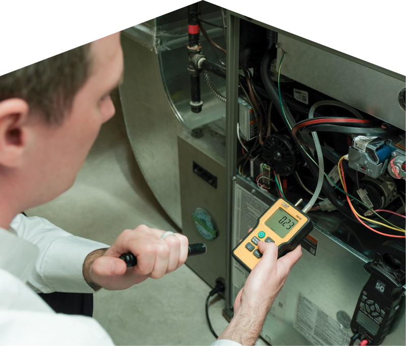 Moore & Russell HVAC specialist performing furnace repair on a heating system, using a digital manometer to check pressure. Moore & Russell HVAC specialist performing furnace repair on a heating sy