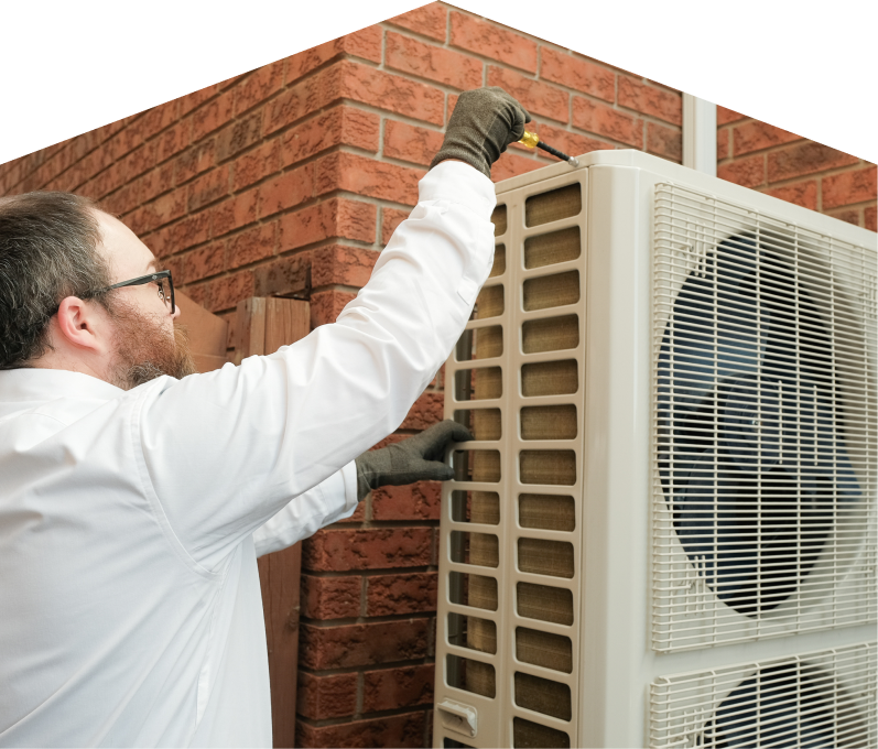 Moore & Russell HVAC specialist using a screwdriver to complete a heat pump installation beside a brick wall. Moore & Russell HVAC specialist using a screwdriver to complete a heat pump installation beside a brick wall.