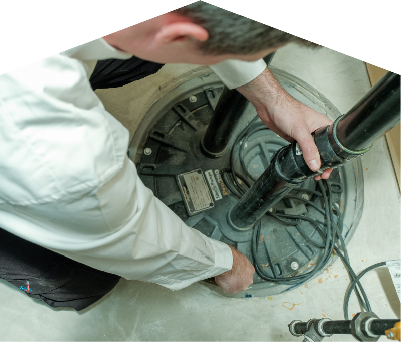 Moore & Russell sump pump specialist secures discharge piping on a sealed basin during a sump pump installation in a basement utility area. Moore & Russell sump pump specialist secures discharge piping on a sealed basin during a sump pump installation in a basement utility area.