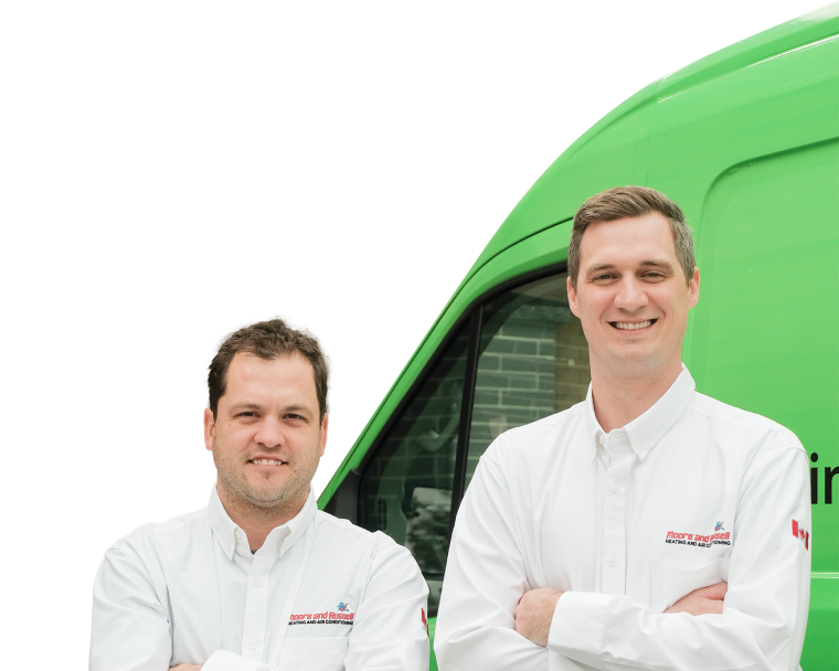 Two Moore & Russell technicians smiling in front of their green service van, wearing issued jackets during an on-site consultation.