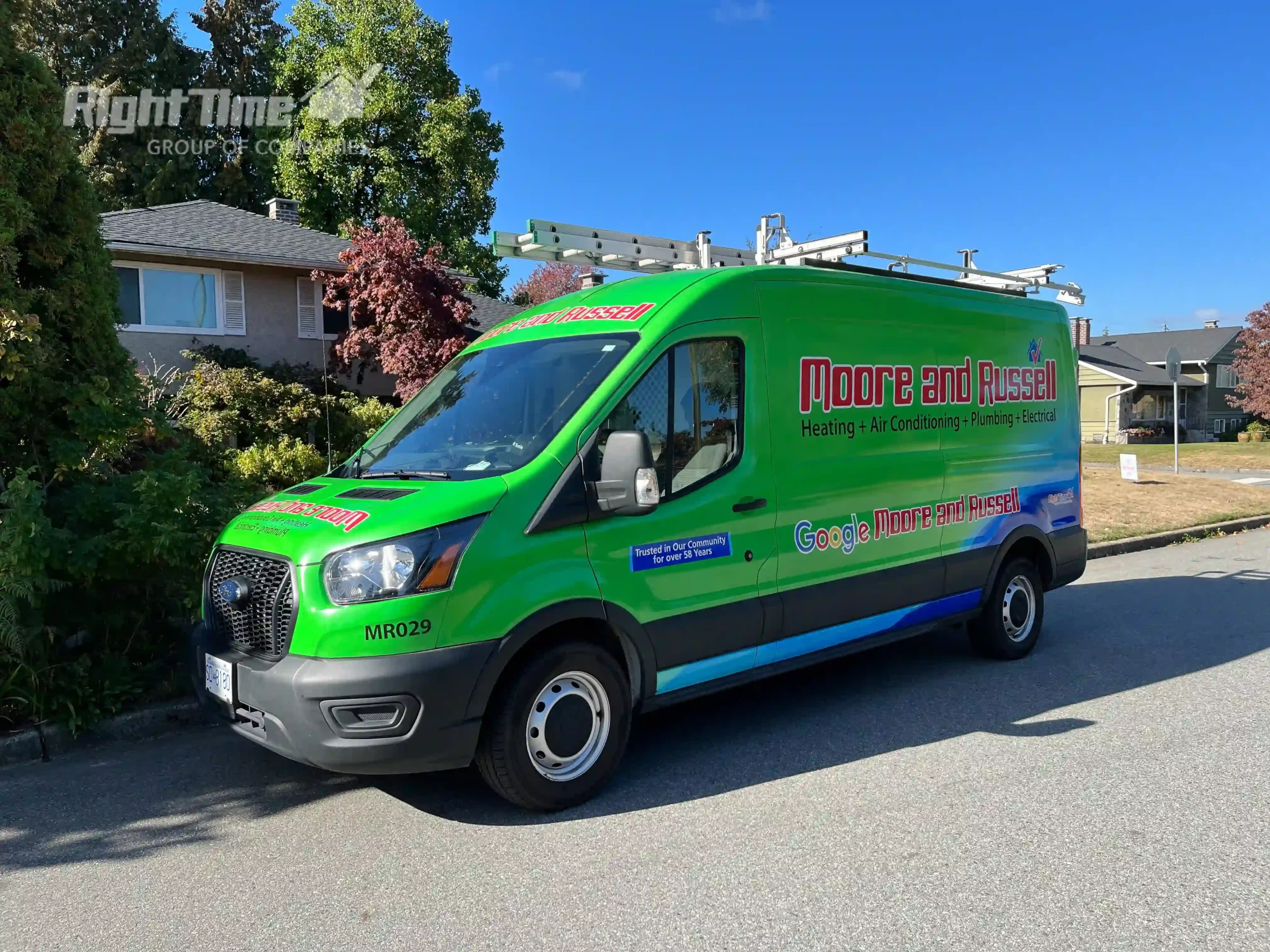 Moore and Russell's green service van is parked on a residential street under a sunny sky in the fall.