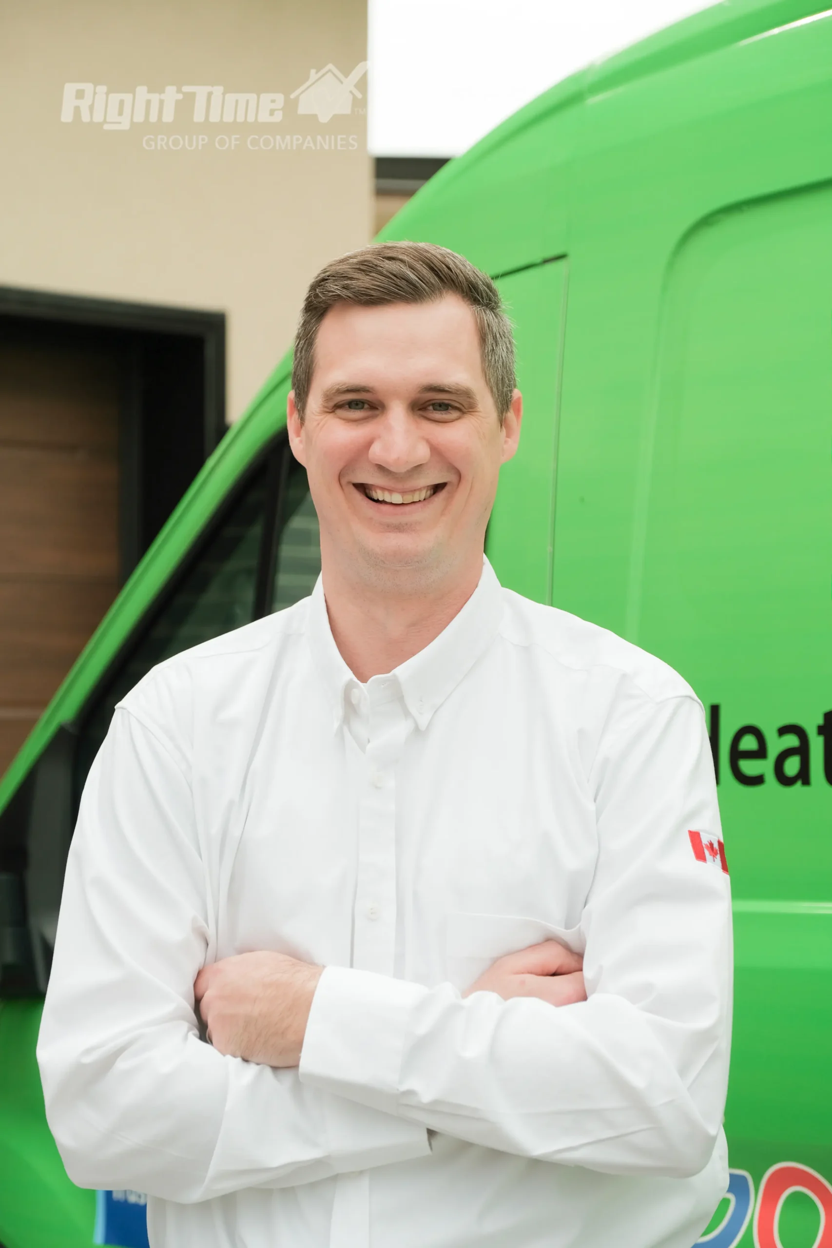Smiling HVAC technician in a white uniform standing in front of a green service van.